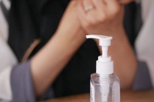 Close-up of Dispenser Bottle with Woman Applying