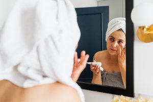 Mirror Reflection of a Woman Applying Face Cream