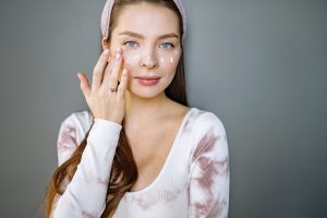 Woman Applying Cream on Her Beautiful Face