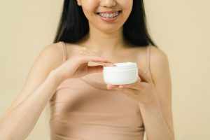 Woman holding plastic container for cream